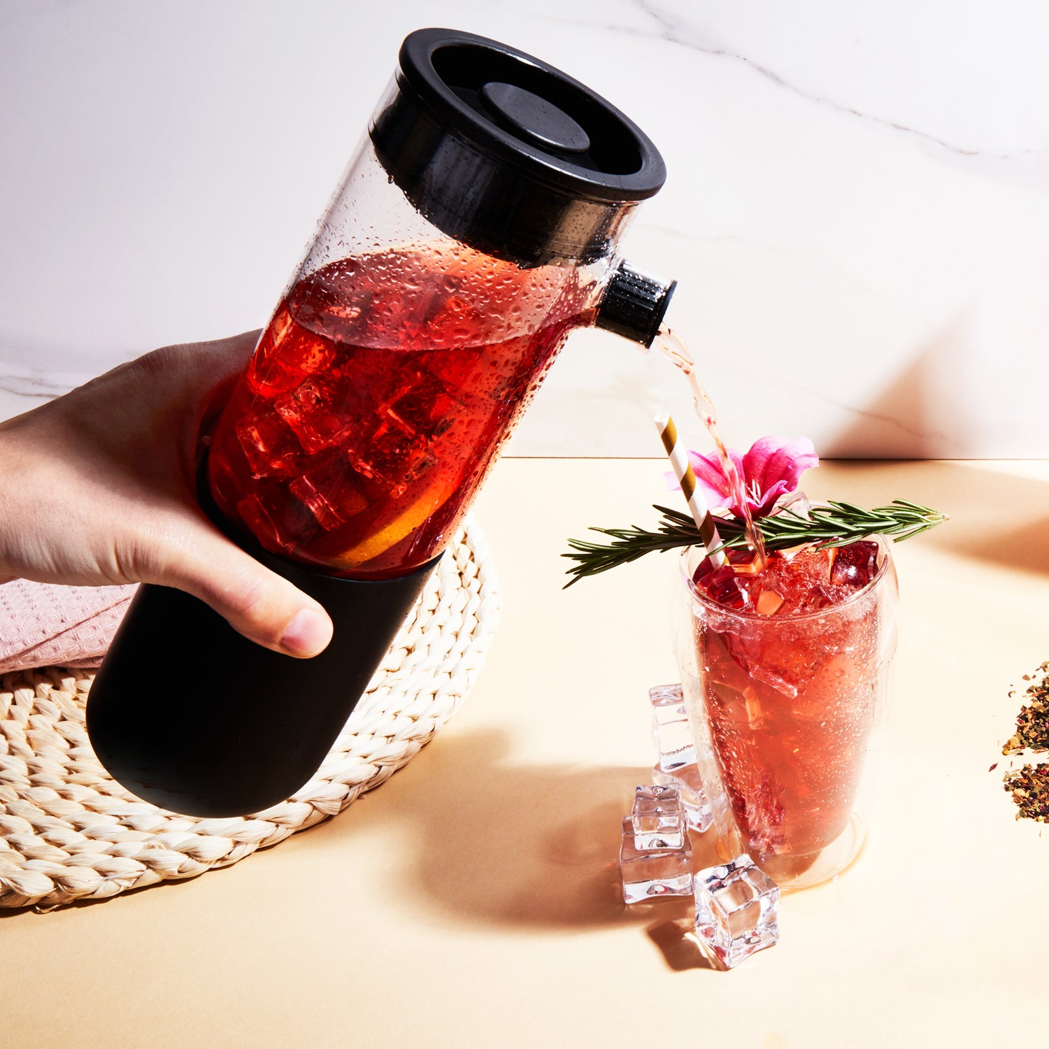 Pouring hot water into a black 'Firebelly Tea' infuser bottle on a table.